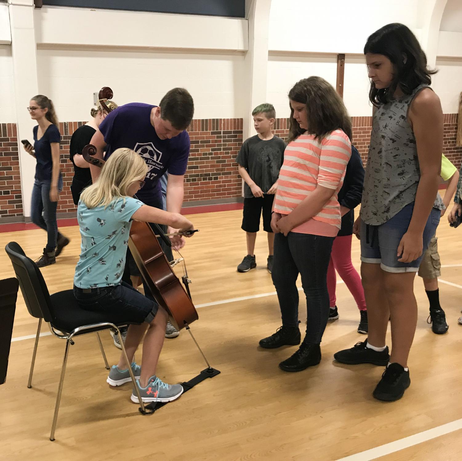 Introducing Music. On August 24th Hornet Orchestra seniors toured elementary schools. Senior Shane Beshears introduces the cello to a fifth grader during the instrument demonstration.